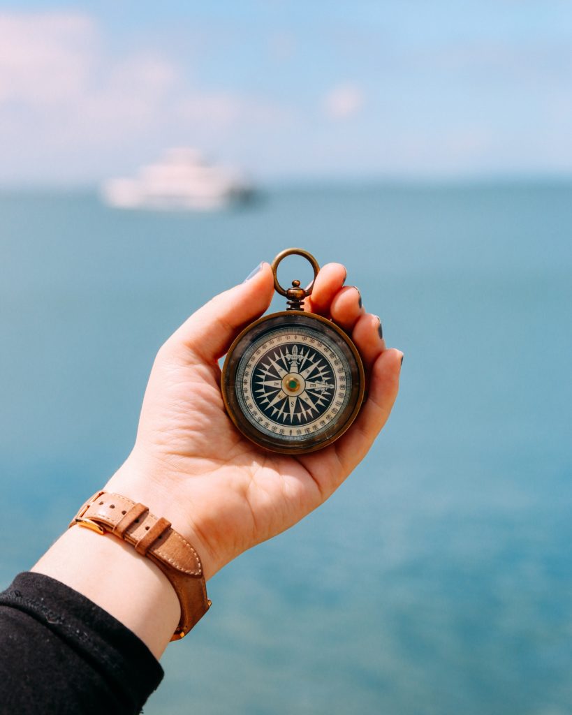 Person holding compass with the sea in the background